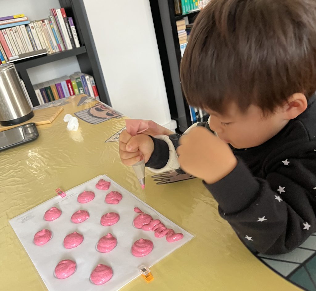 Child piping colorful macaron batter creatively, hands-on experience
