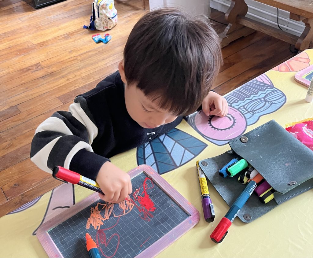 Child drawing at a small table with colored pencils during a baking break