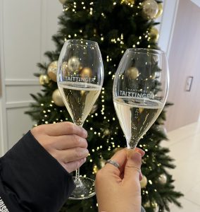 Two Champagne glasses raised in front of a Christmas tree, Taittinger Reims